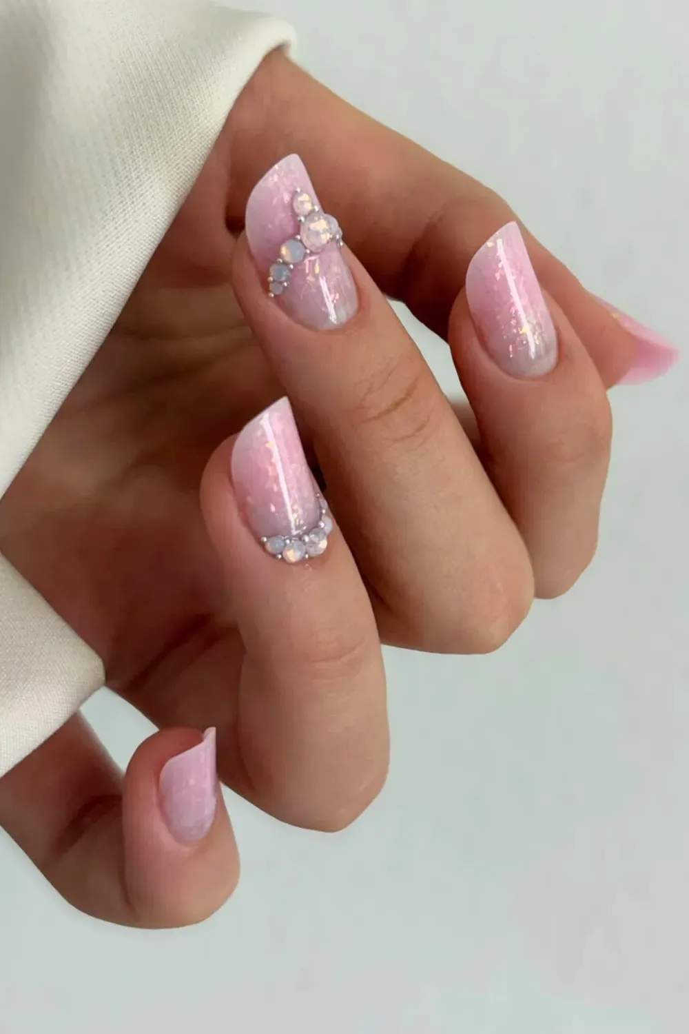 Jeweled Cuticle Glam - Angled lipstick shape nails in light pink glitter with chunky gems at the cuticle.