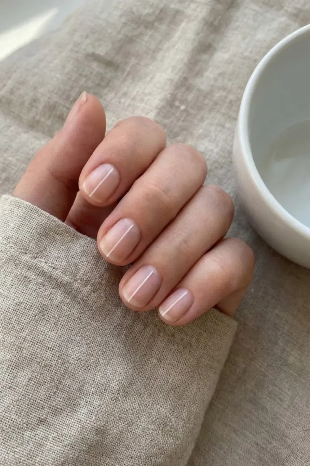 Minimal Vertical Line Nude – Short square manicured nails with a sheer base and a single thin white vertical line down the center.