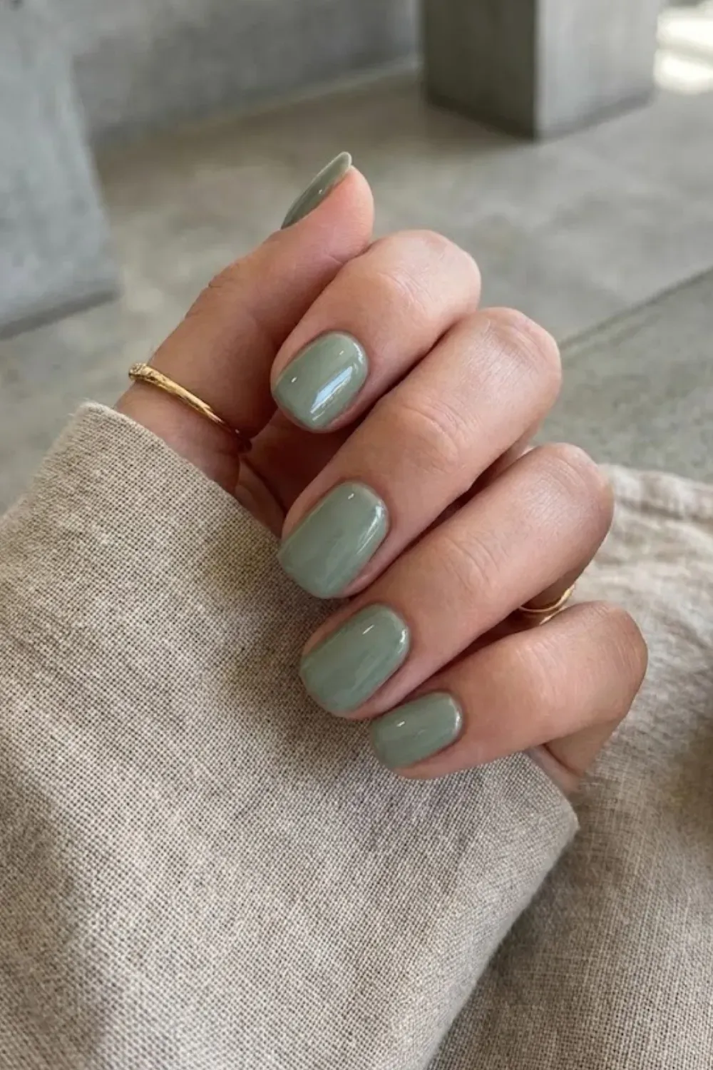 Glossy Sage Green Short Nails – Short square nails painted in a muted glossy sage green, holding a ceramic mug.