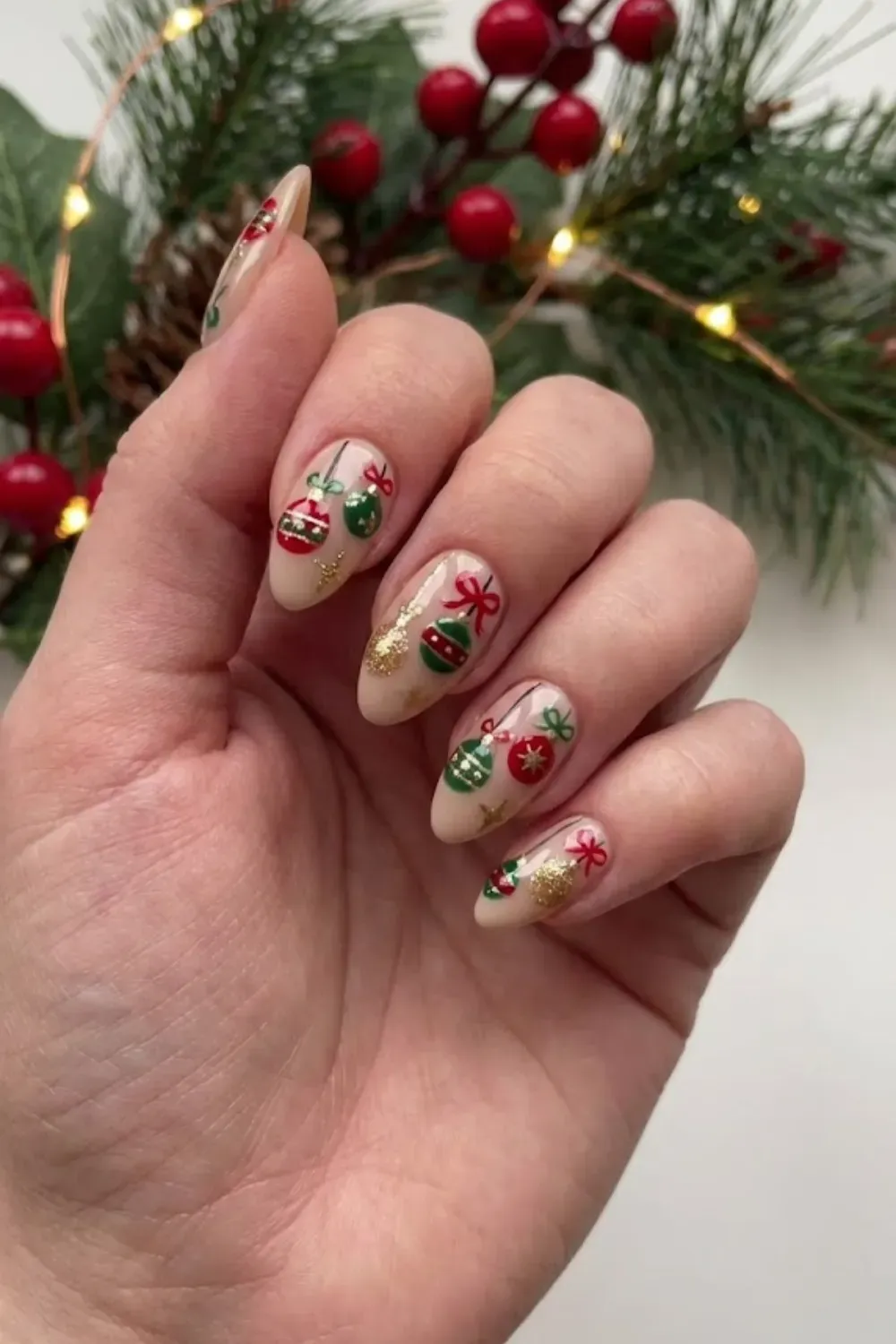 Nude Nails with Christmas Ornament Art - Nude almond nails decorated with detailed red and green hanging Christmas ornaments and bows.