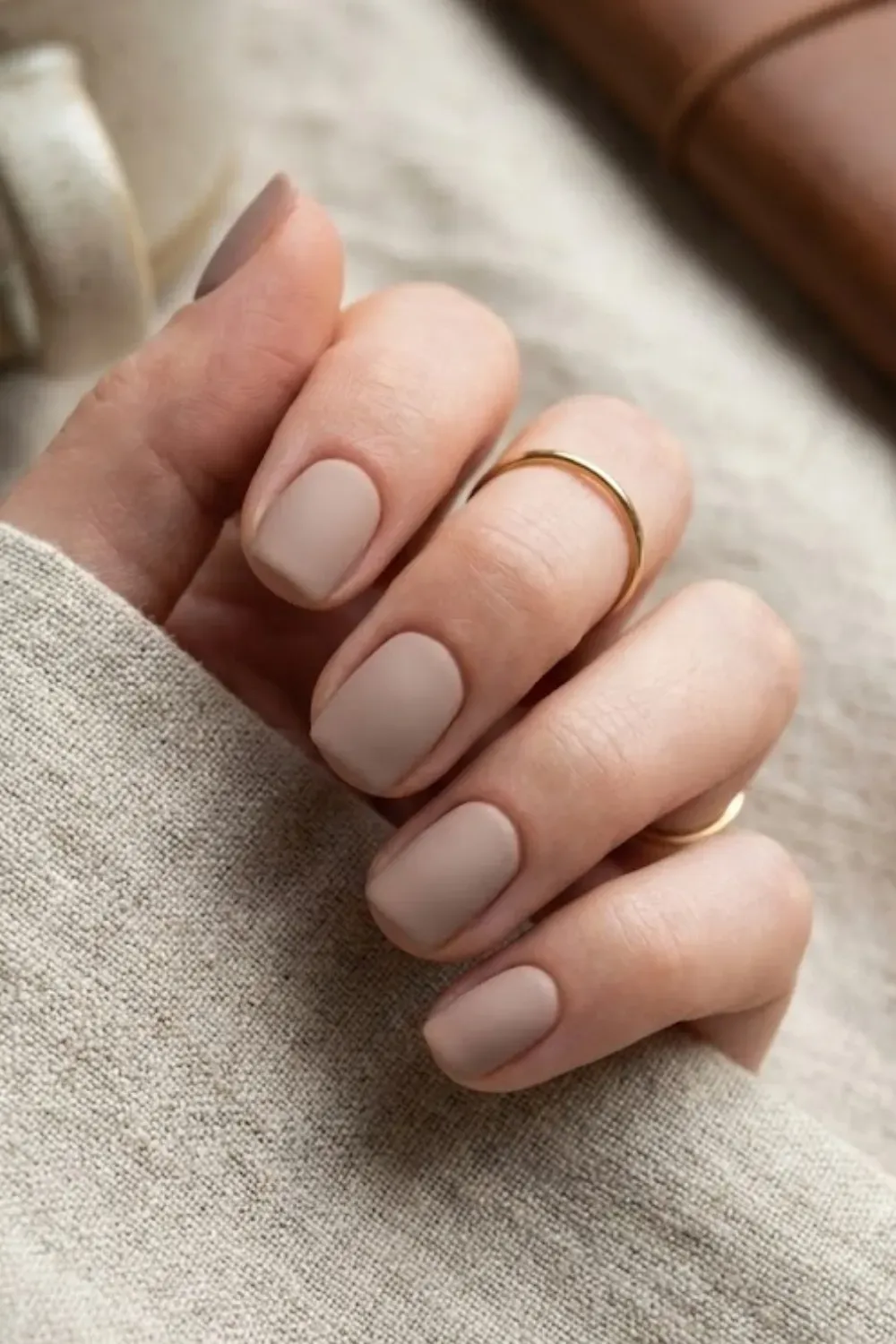 Matte Taupe Short Square Nails – Short square nails with a matte finish in a soft taupe brown shade, resting on a beige linen fabric.