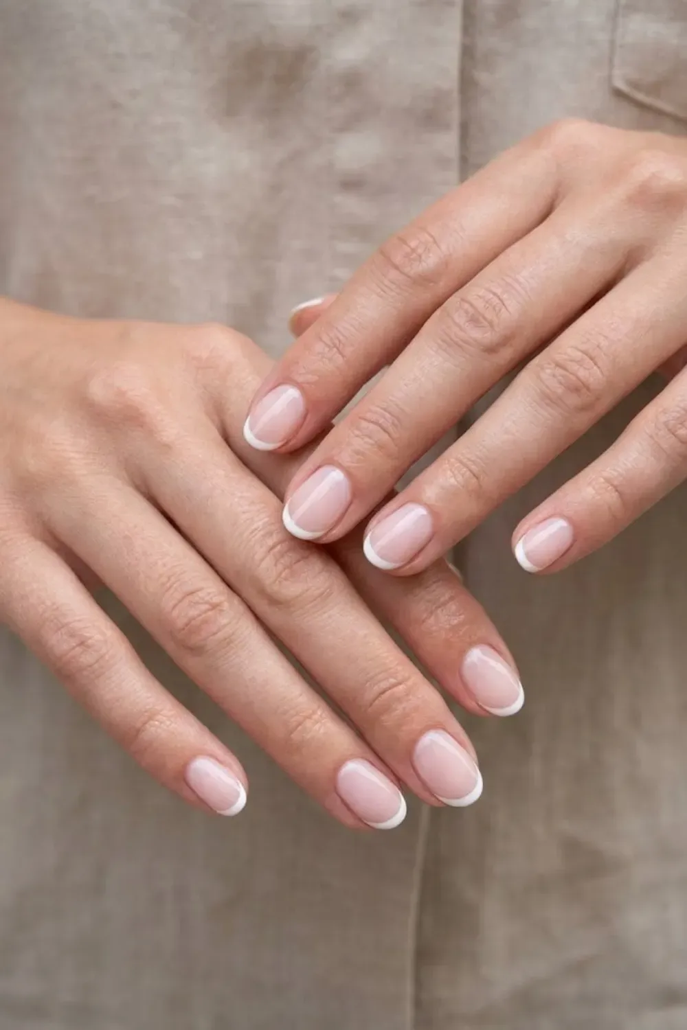 imple-white-micro-french-tip-nails - Simple French tip manicure on short nails with thin white tips over a sheer pink base.
