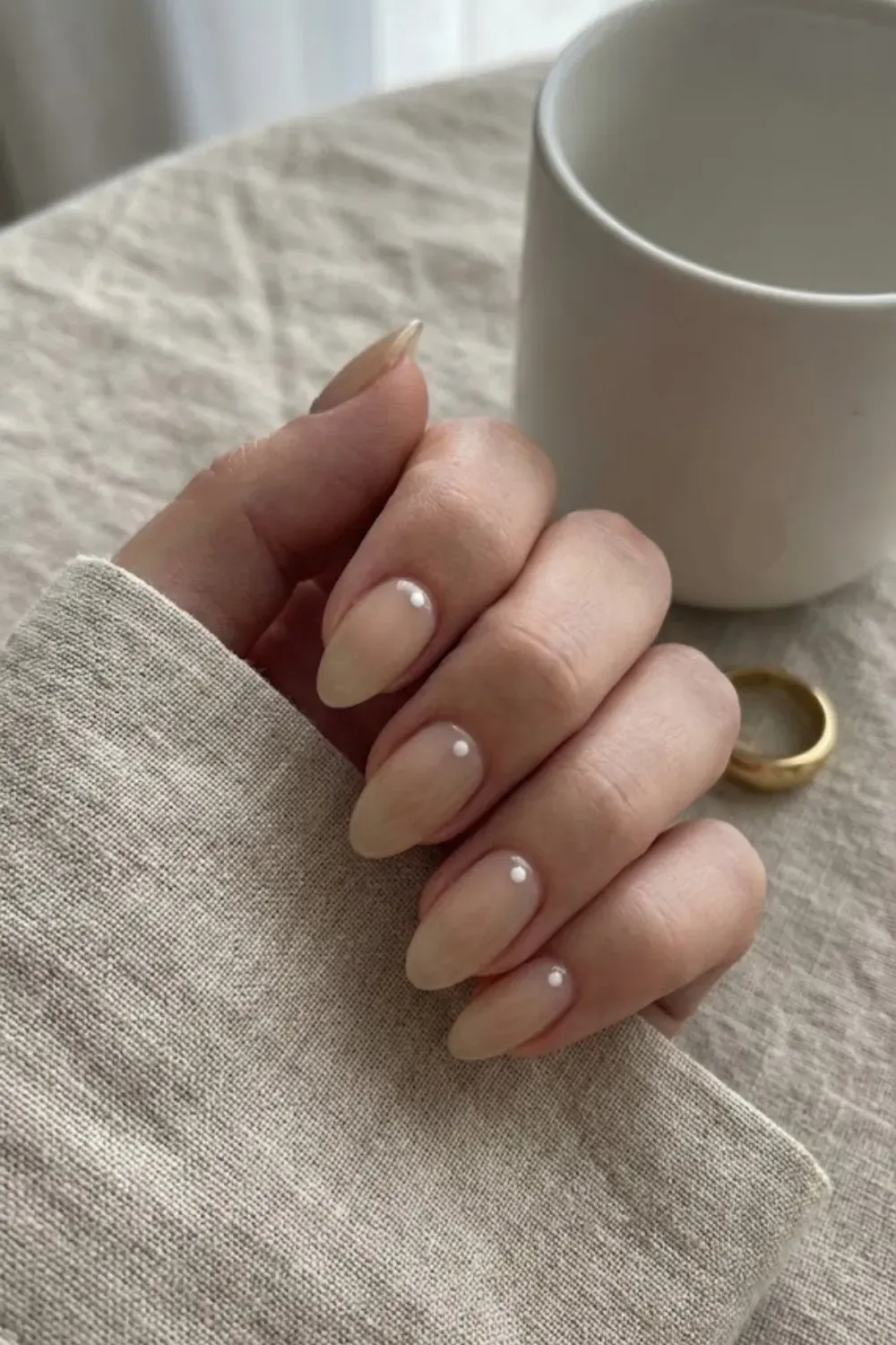 Single White Dot Accent – Almond sheer beige nails featuring a single minimalist white dot at the base of each nail.