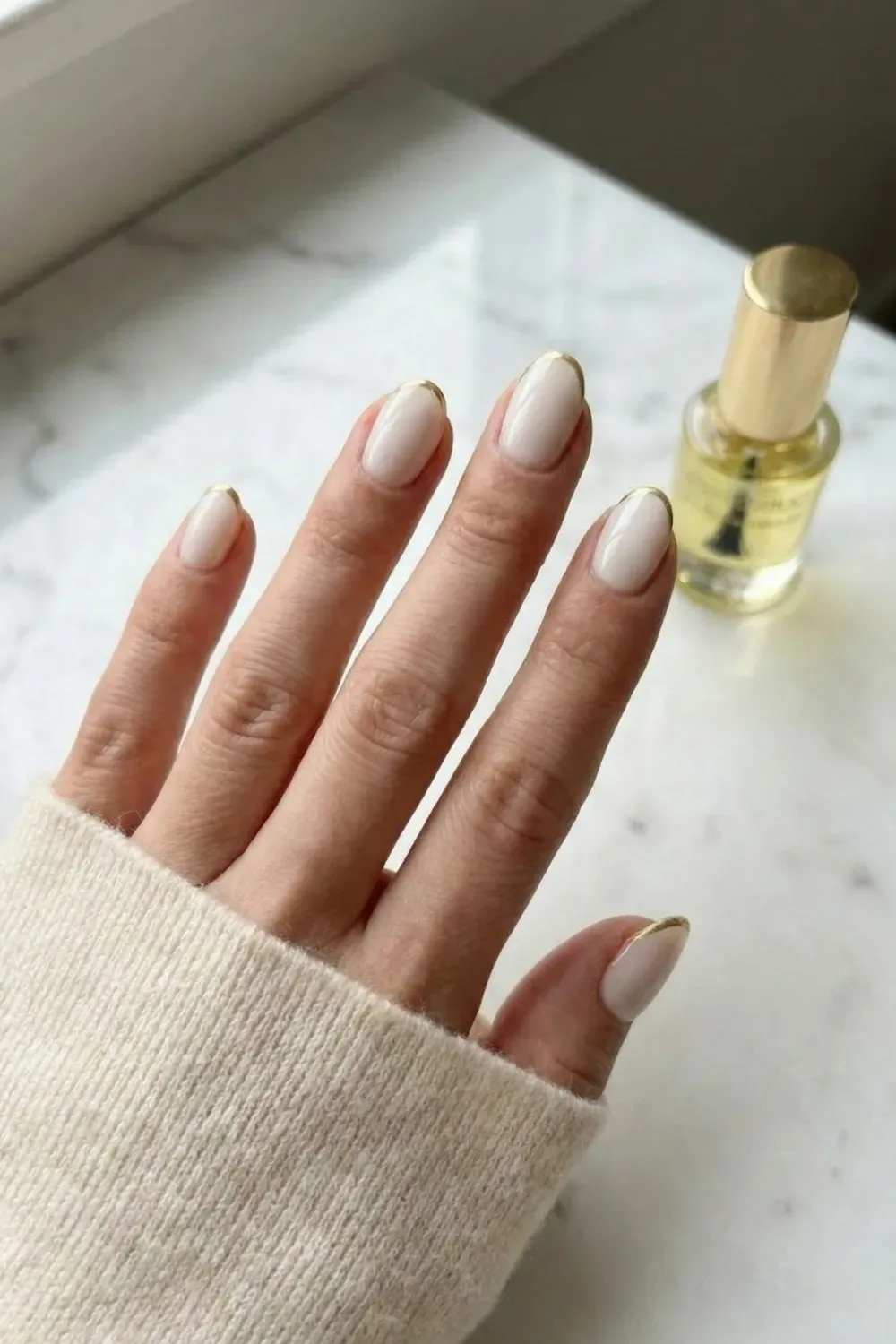 Milky White with Gold Micro-Tip - Short almond nails painted milky white with an ultra-thin metallic gold chrome French tip.