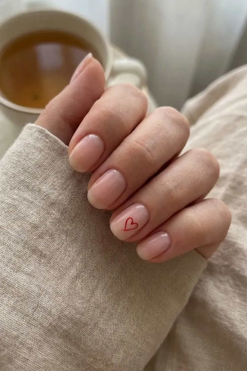 Minimal Red Heart – Short natural nails with a sheer gloss and a tiny outline of a red heart on the ring finger.