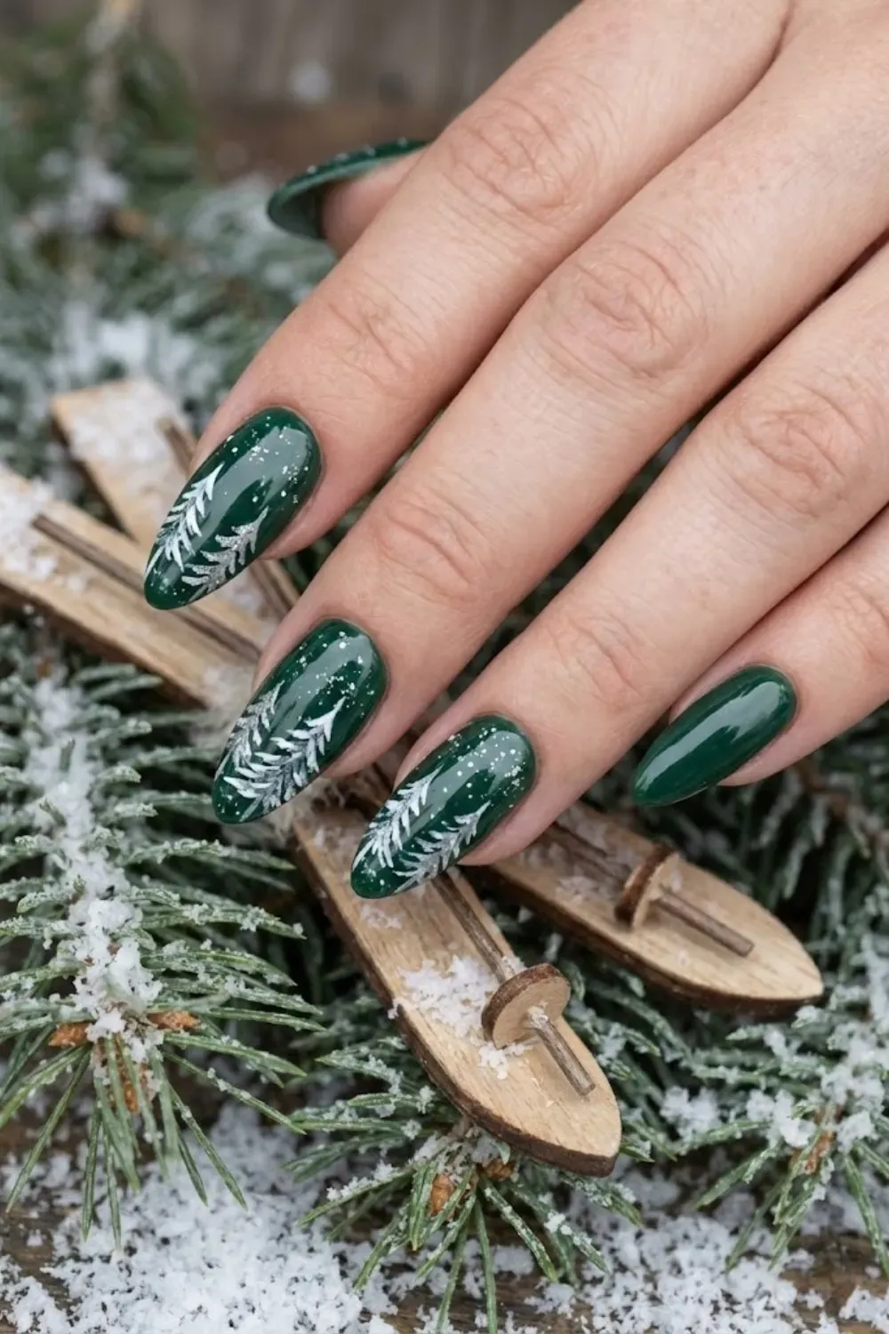 Frosty Pine Tree Nails – dark green almond nails with painted white snowy pine trees