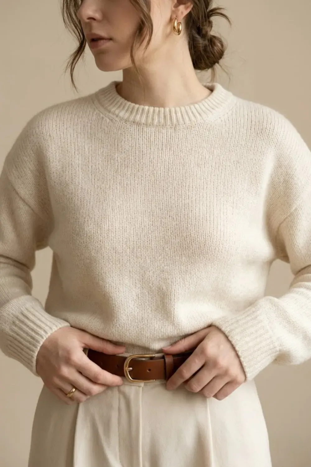 Close up detail of minimal gold hoop earrings and leather belt quiet luxury accessories.