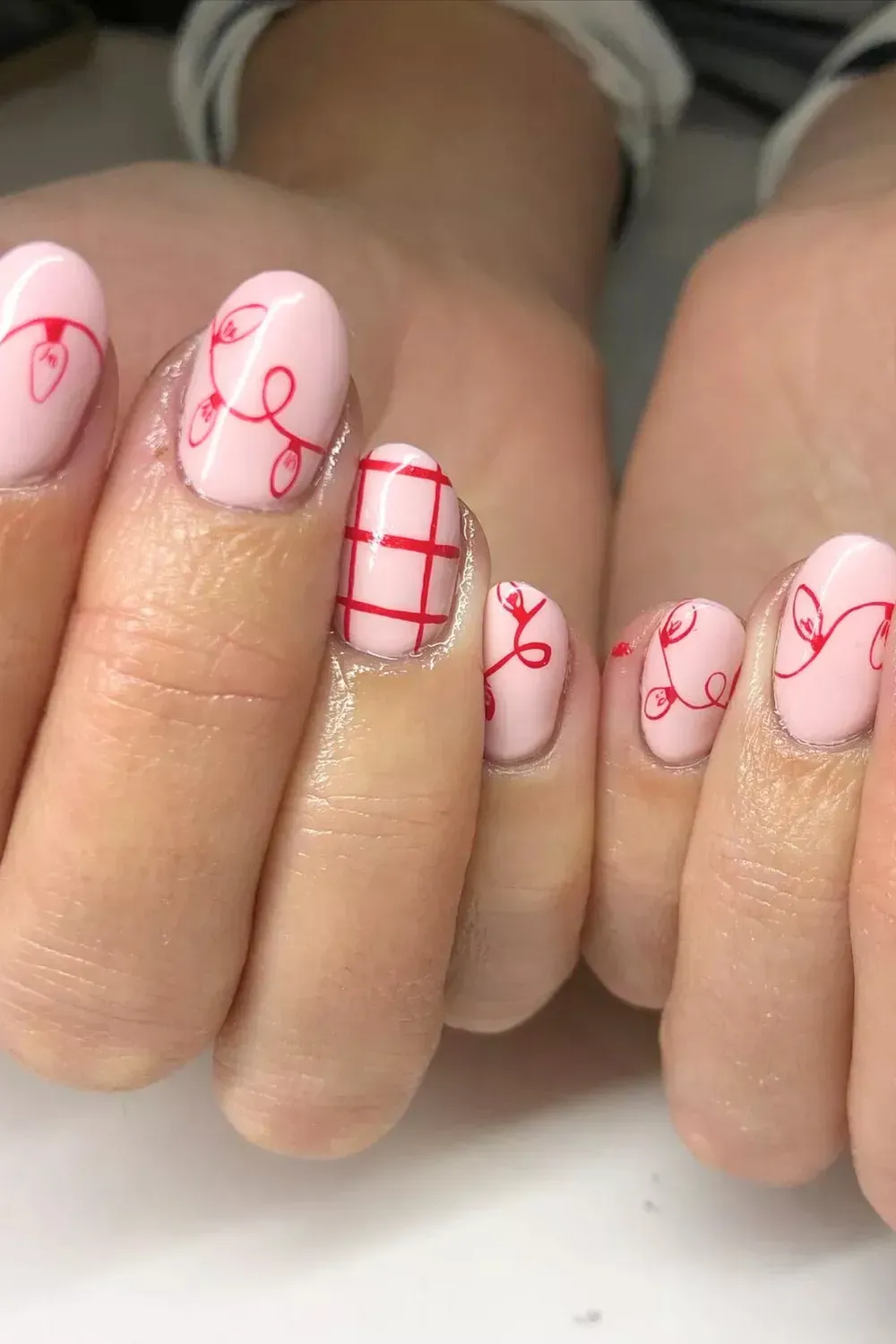 Pink Nails with Red Christmas Lights - Pink nails featuring hand-painted red string lights and plaid accents.