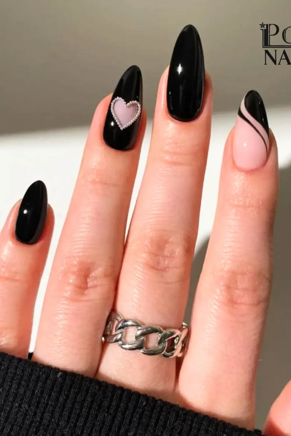 Glossy Black and Pink with Chain Heart	Long almond nails with glossy black base, pink accent nail with black swirls, and black nail with pink beaded heart chain