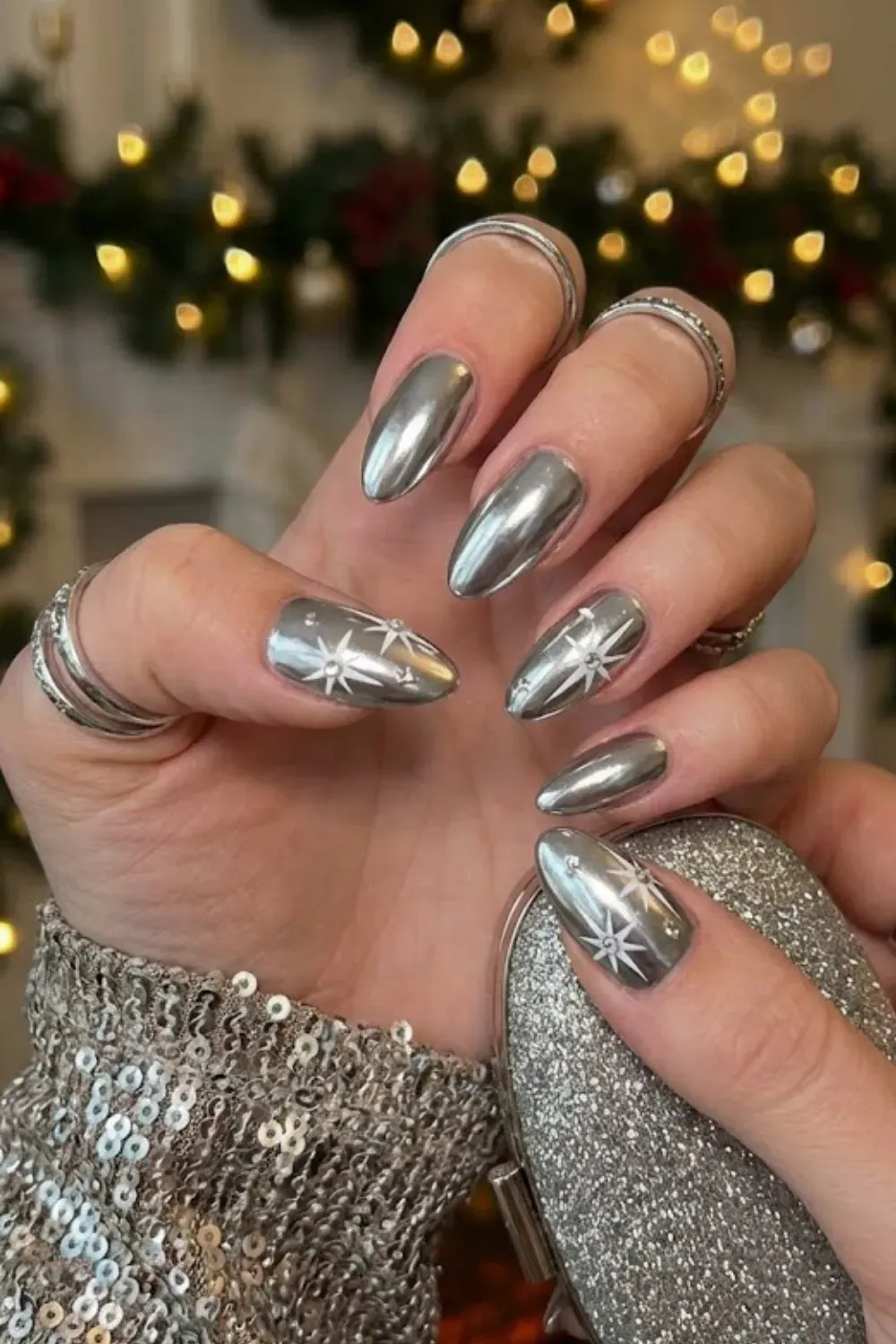 Silver Chrome Nails with White Stars - Sleek silver chrome almond nails featuring modern white starburst designs.