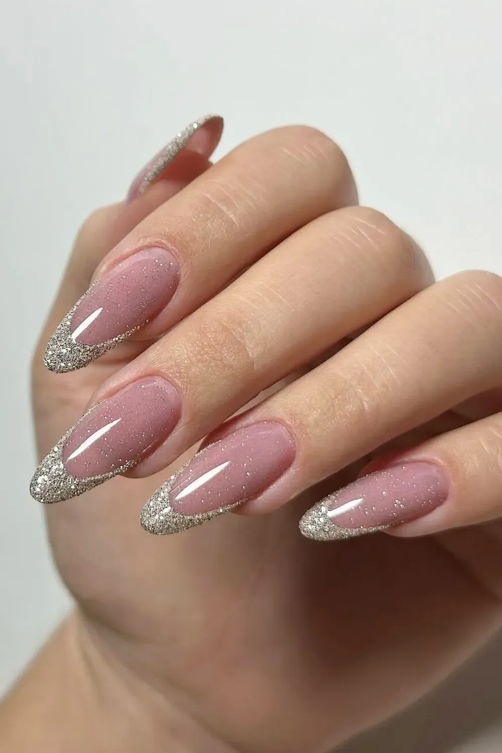 Reflective Glitter French - Elegant almond nails with a nude pink base and reflective silver glitter french tips.