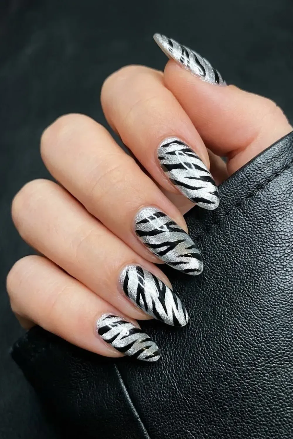Silver cat eye nails with bold black zebra stripe nail art
