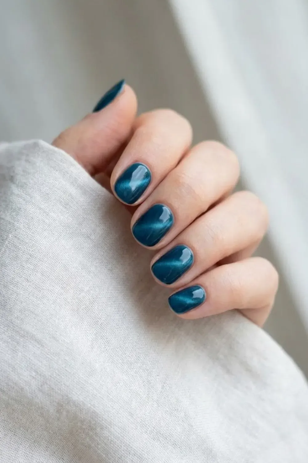 Deep ocean teal cat eye nails with subtle magnetic shine on short glossy nails