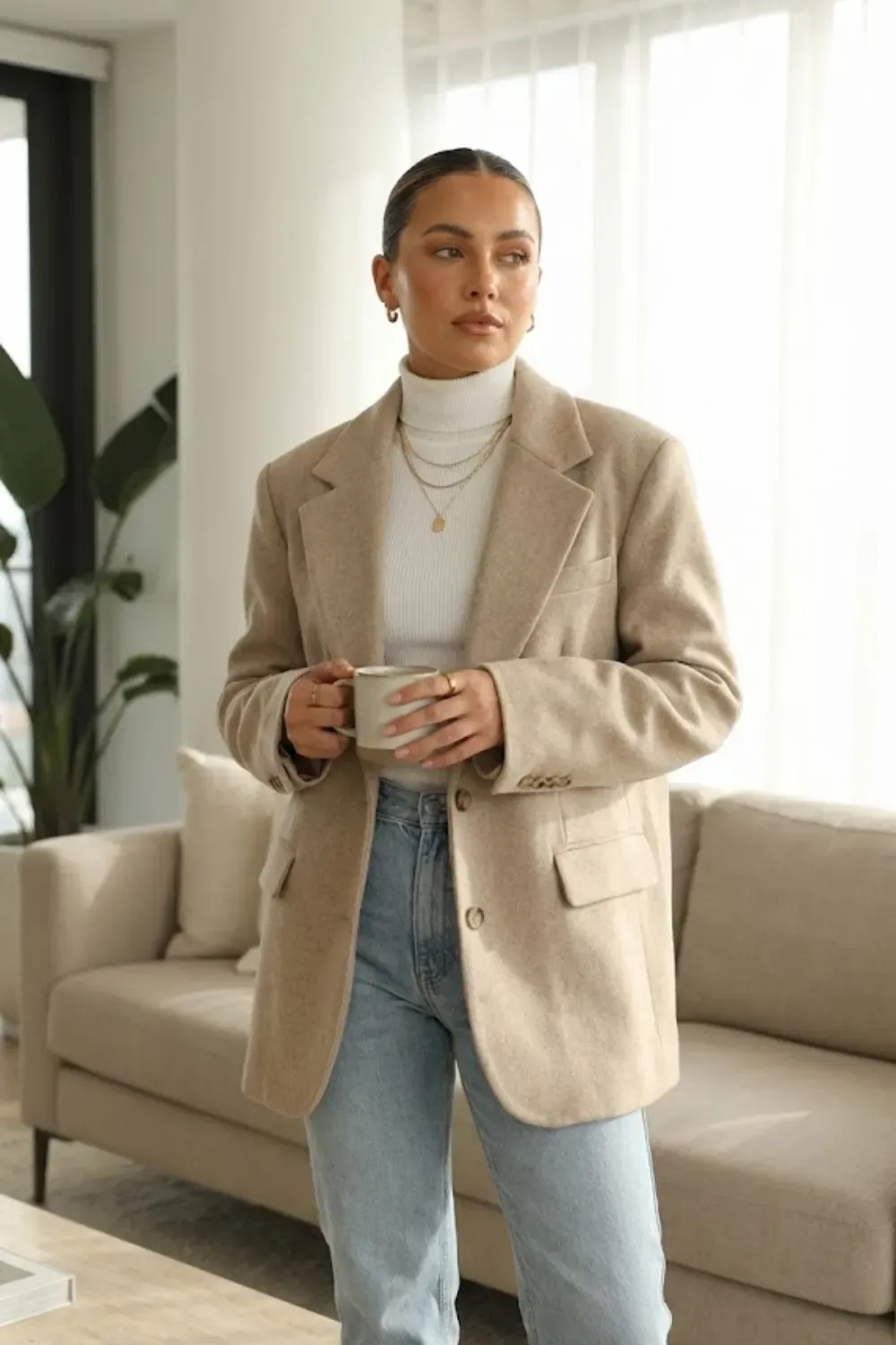 Oversized Beige Blazer & Turtleneck – Chic layered outfit with an oversized beige blazer over a white turtleneck and light jeans.