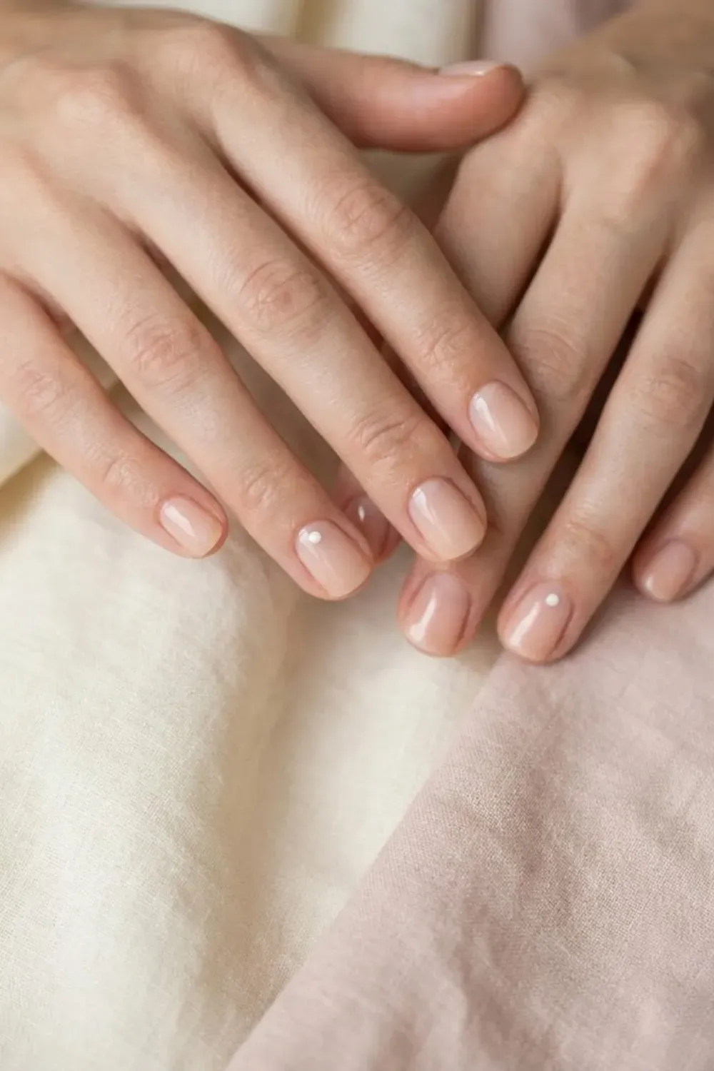 minimal-nail-art-white-dot-accent - Minimal manicure with nude nails and one accent nail featuring a small white dot, clean girl aesthetic.