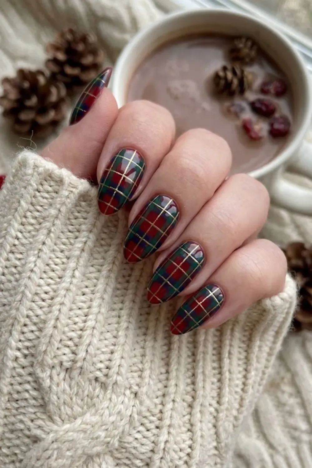 Red and Green Tartan Plaid Almond Nails - Festive almond nails featuring a traditional red and green tartan plaid pattern with gold glitter lines.