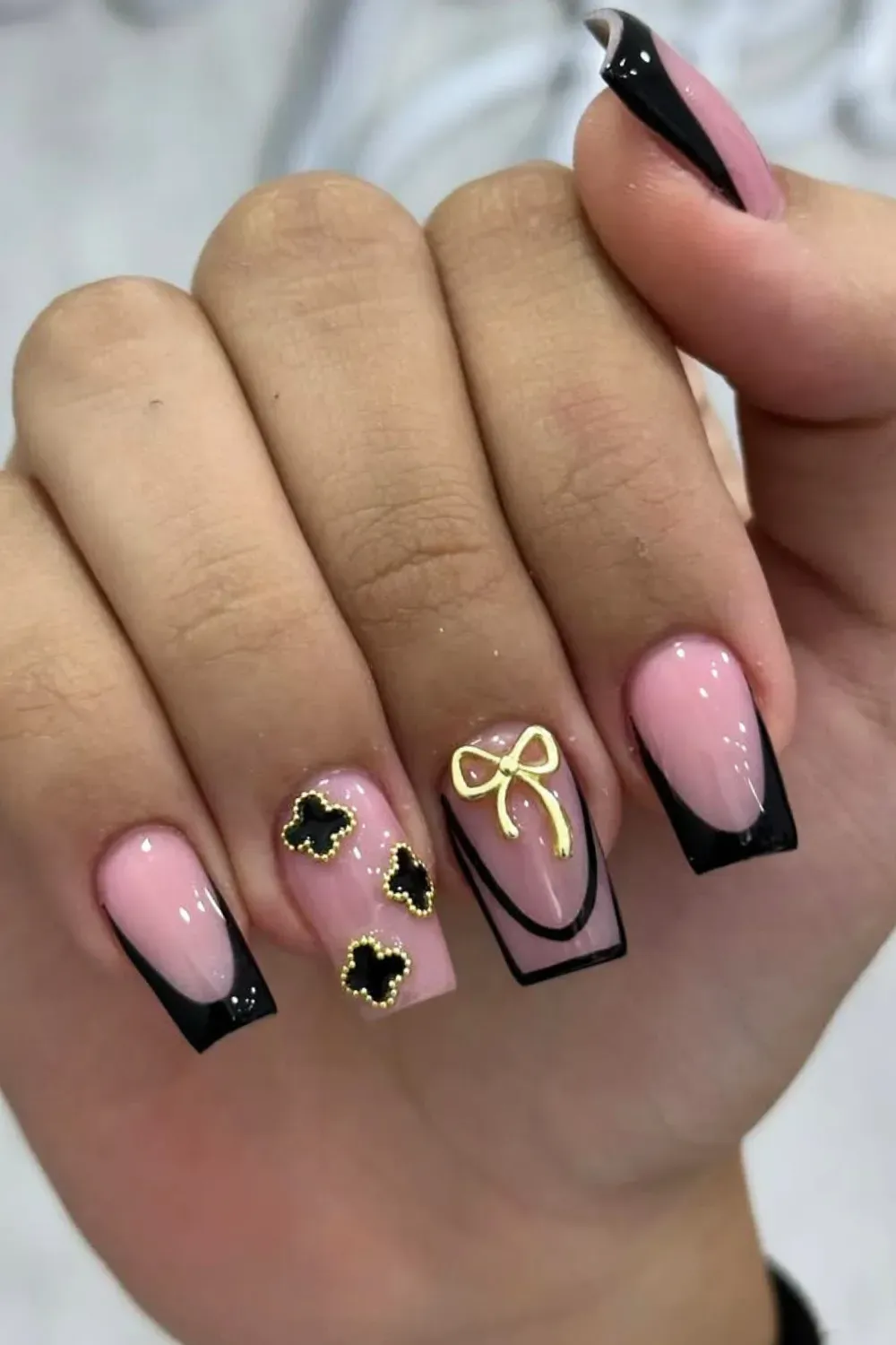 Coquette Bows and Clovers	Pink nails with black french, gold bows and clovers