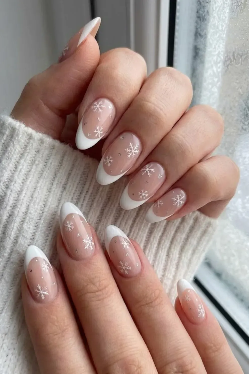 Delicate White Snowflake Nails — almond nails with white French tips and intricate painted white snowflakes.