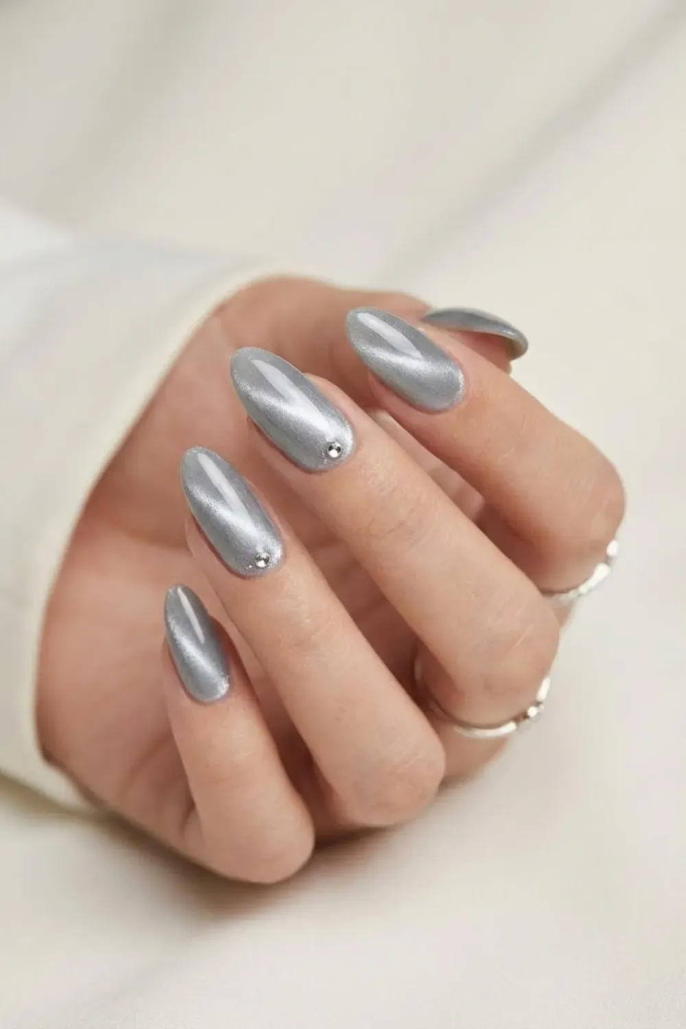 Minimalist silver cat eye nails with rhinestone accents near the cuticle