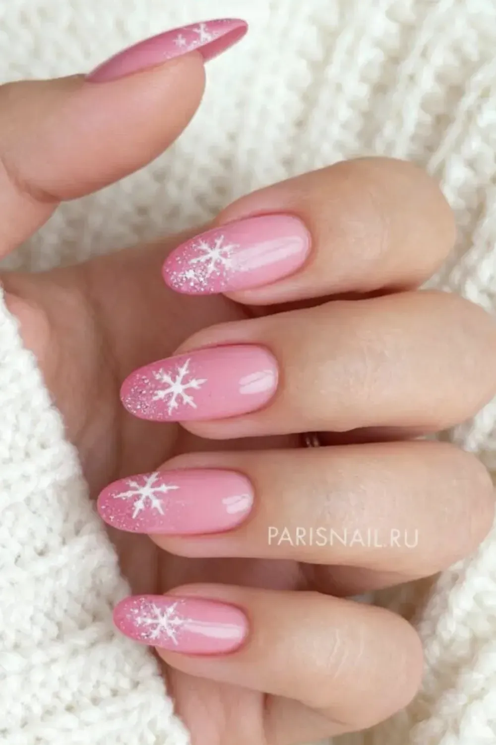 Snowfall Cuticle Art - Oval pink nails featuring white snowflake nail art painted near the cuticle.