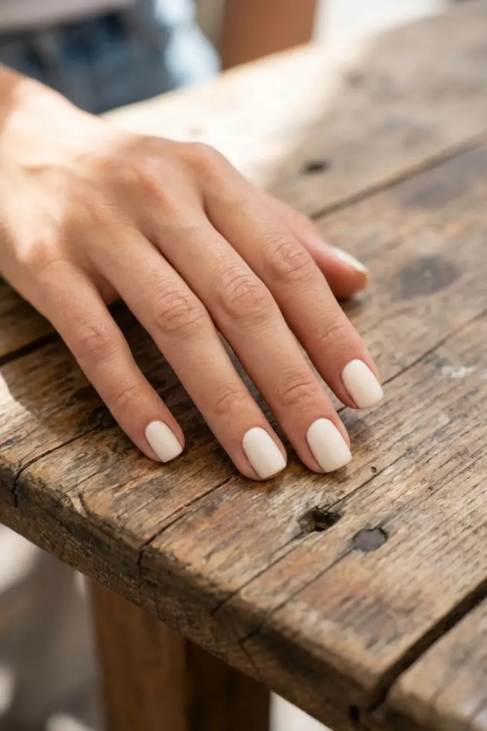 Cloud White Cream Square - Short square nails painted in a soft off-white cream polish, resting on a wooden surface.