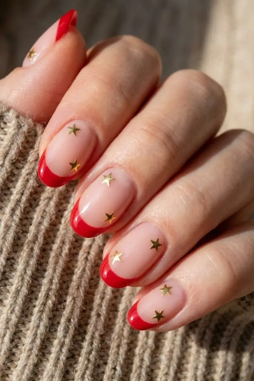 Gold Star Red French Nails — oval nails with red French tips and tiny gold stars scattered on the base.