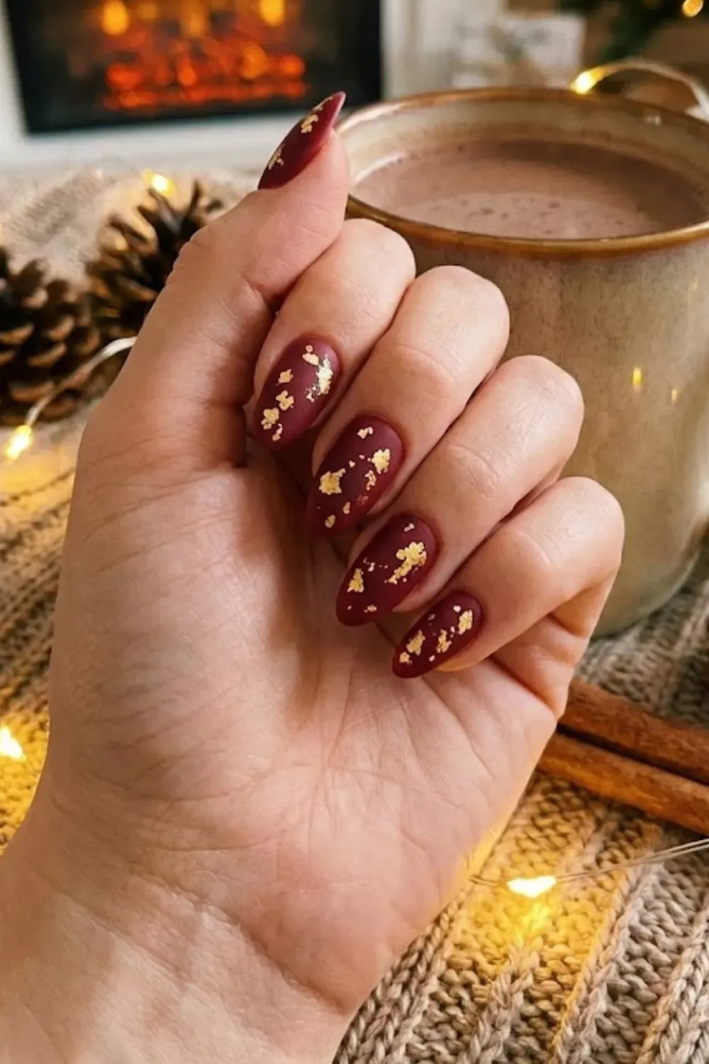Matte Burgundy Nails with Gold Foil Accents - Sophisticated matte deep red almond nails decorated with luxurious gold foil flakes.