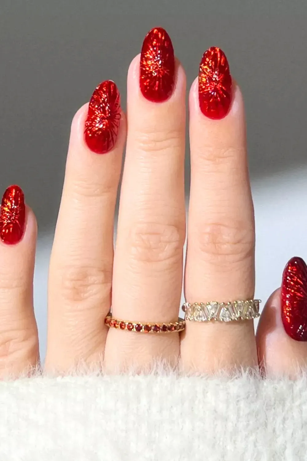 Textured Red Glitter Firework Nails - Oval nails featuring a textured, crushed glitter finish in vibrant cranberry red.