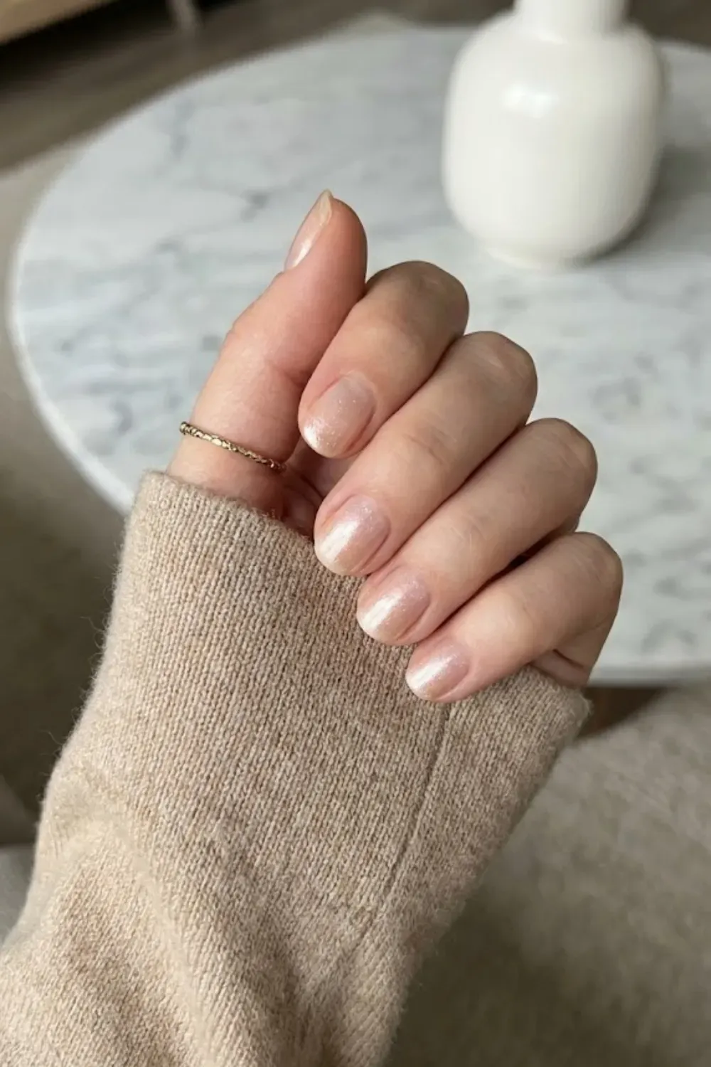 Champagne Shimmer Nude – Short oval nails painted in a soft sparkling champagne nude shade.