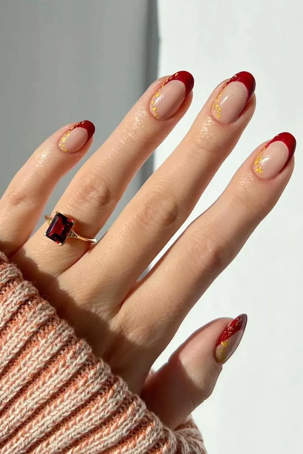 Red French Manicure with Gold Foil - Classic red french tips accented with scattered gold foil flakes on a nude base.