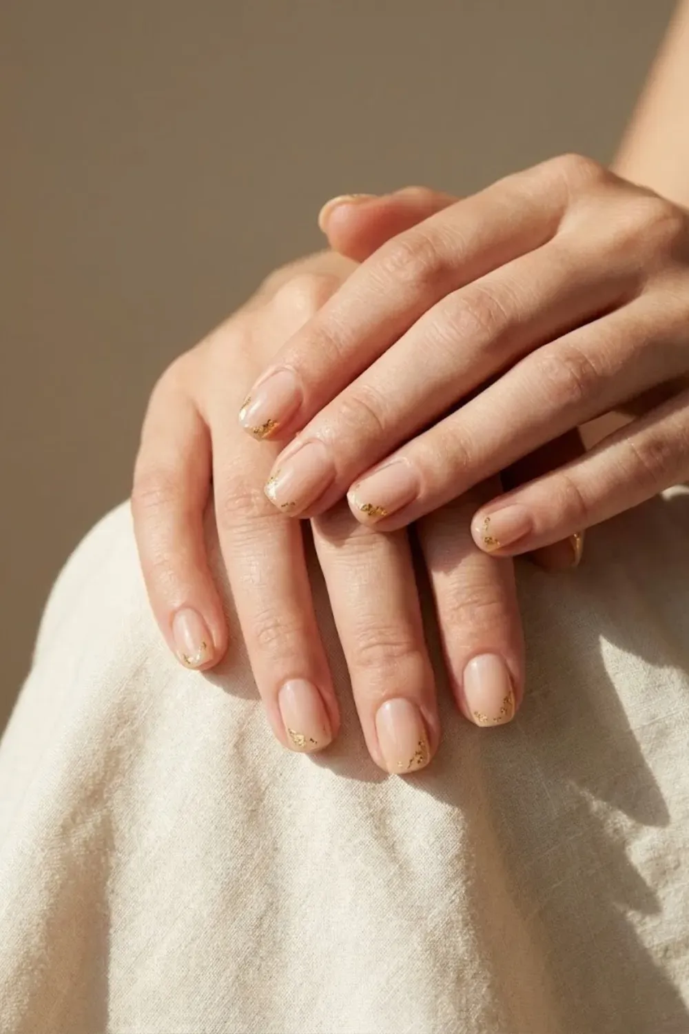 nude-nails-gold-foil-accent-luxury - Short nude nails with subtle gold foil accents, luxury minimal nail art style.
