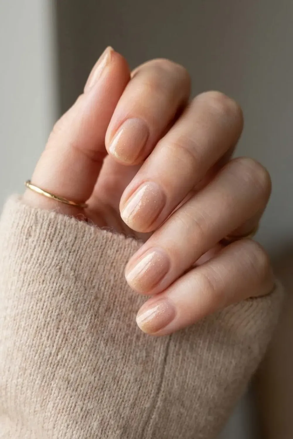 Sheer Shimmer Nude Round - Close up of short round nails with a subtle shimmer nude polish that looks expensive and polished.