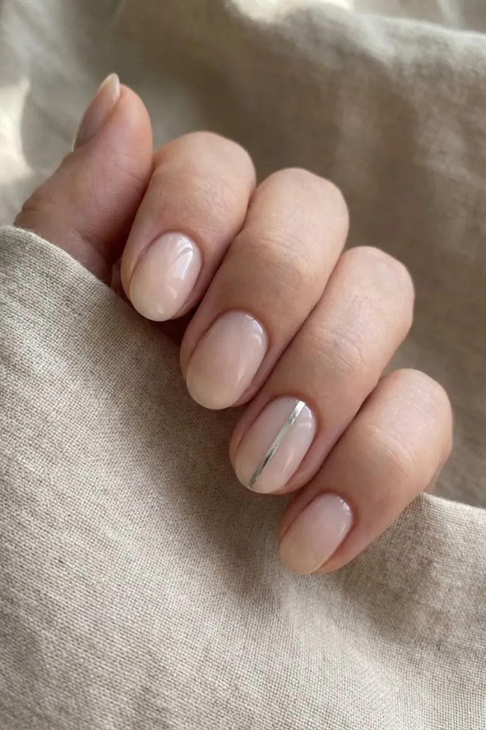Milky Nude with Silver Line Accent - Short oval nails in milky nude featuring a minimalist vertical silver line accent on the ring finger