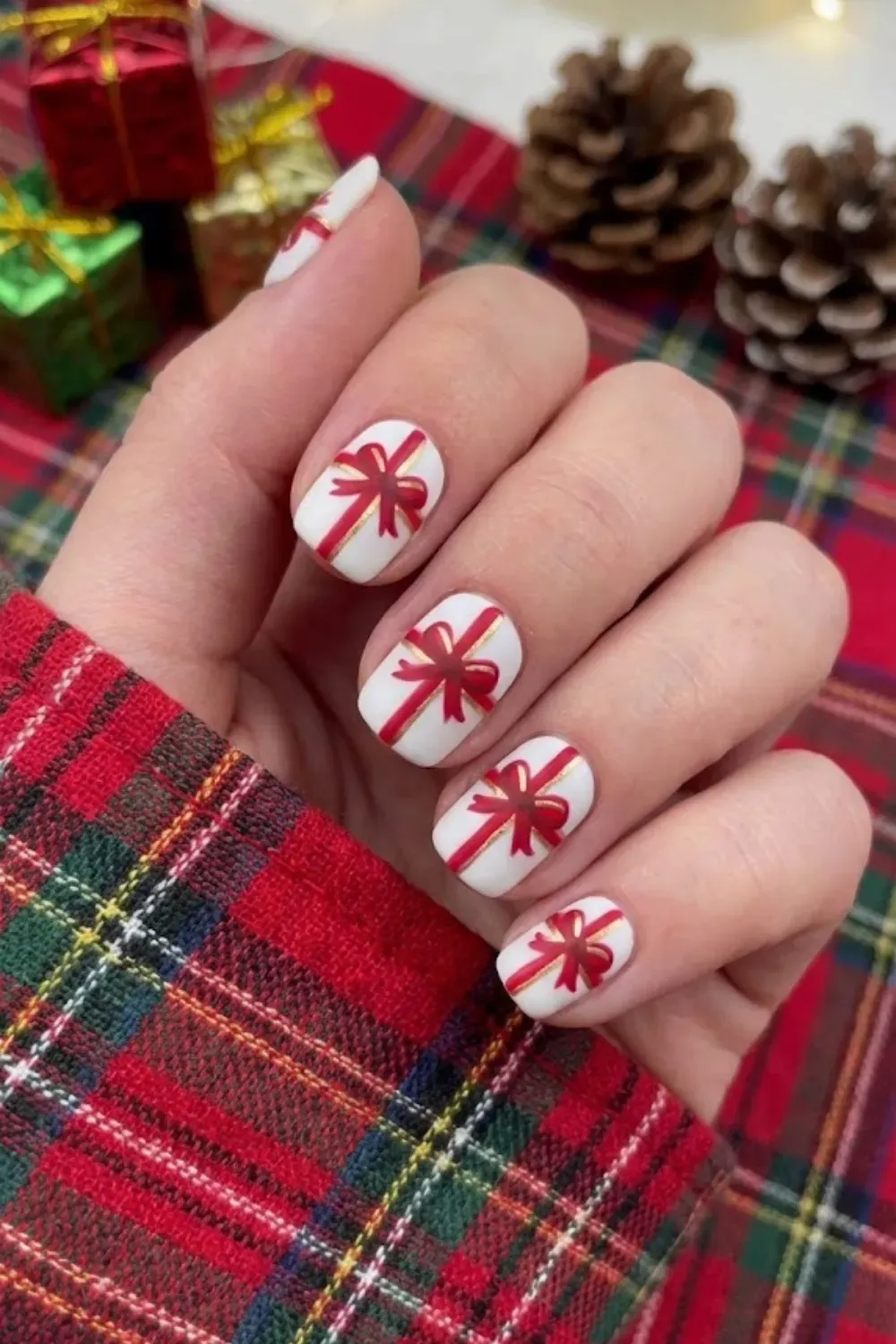 Gift Wrapped Red Ribbon Bow Nails - Short square nails with a white base featuring festive red ribbons and bows resembling wrapped gifts.