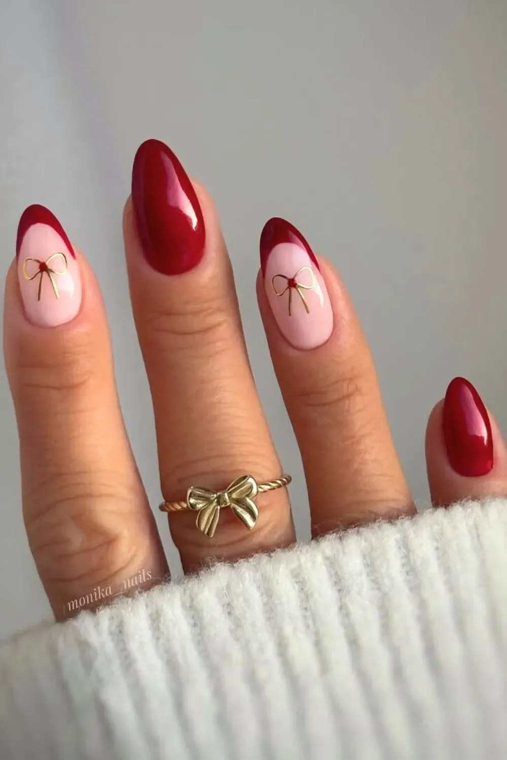Coquette Pink and Red French with Bows - Almond nails with pink base, deep red french tips, and gold wire bow decals