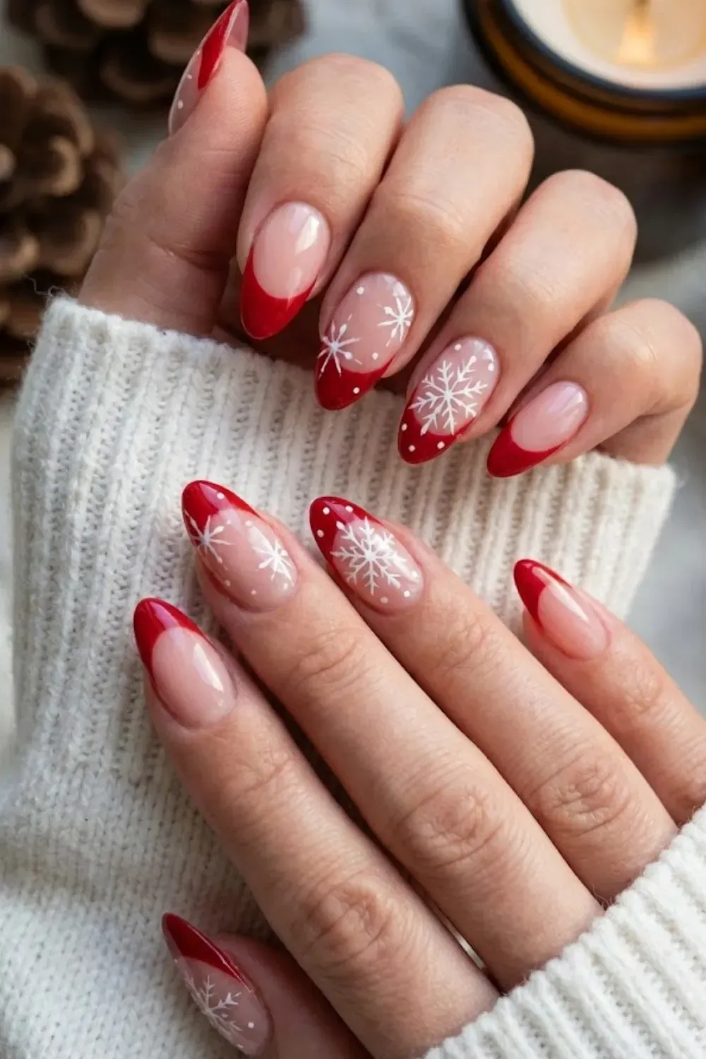 Red Tip Snowflake Nails — almond nails with red French tips and delicate white hand-painted snowflakes.