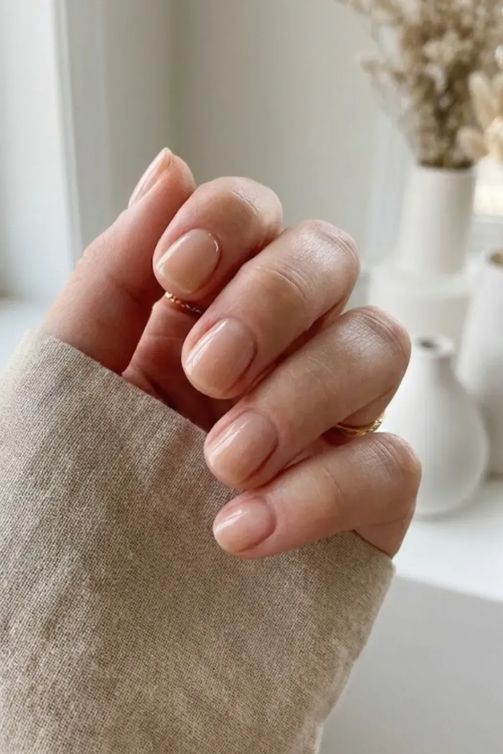 Short natural nails with a sheer nude polish, very clean and minimalist.