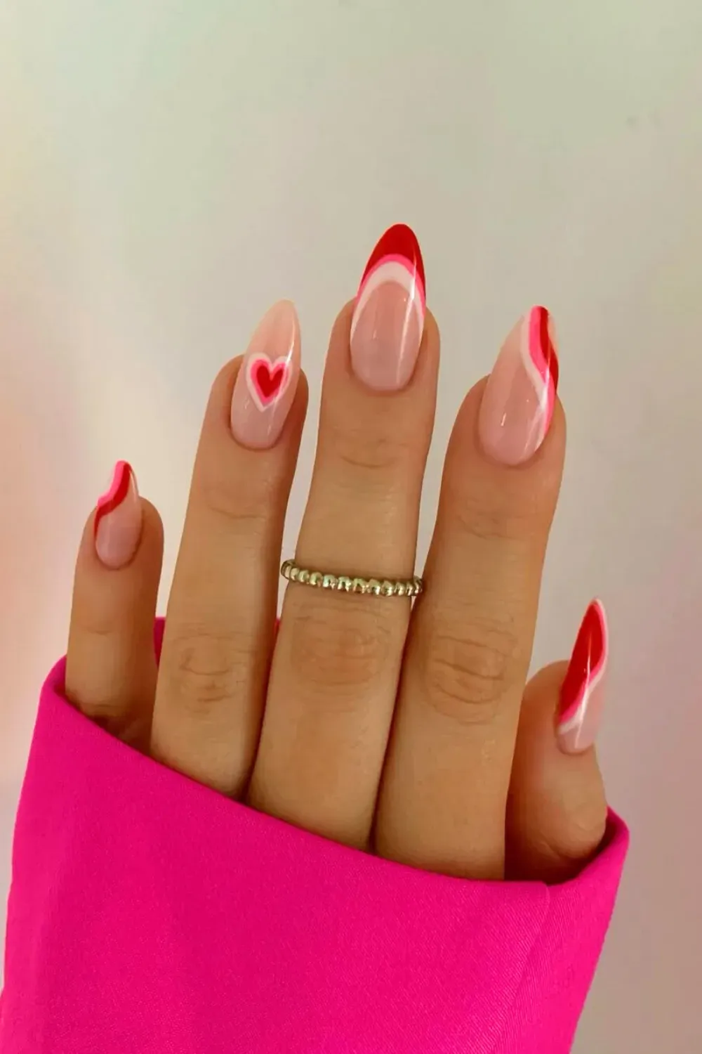 Pink and Red Swirl French with Heart Center – Almond nails with pink and red abstract swirl french tips and a central heart design.