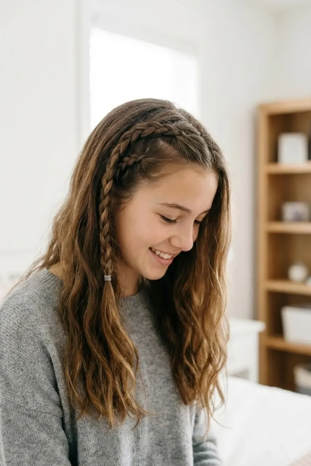 Double Side Braids Detail - Girl smiling looking down, showing two small accent braids on the side of her head.