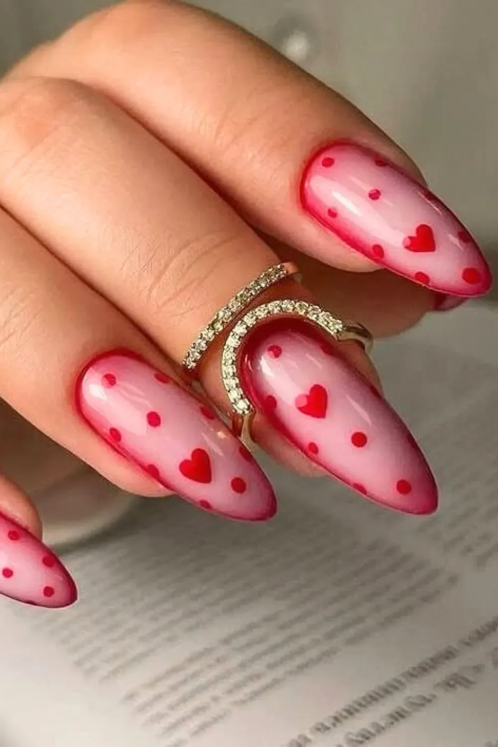 Pink Jelly Aura Nails with Red Polka Dots – Pink jelly aura almond nails featuring a playful pattern of red polka dots and hearts.