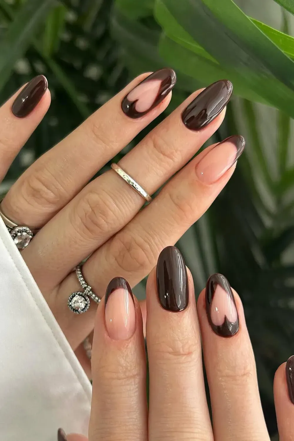 Chocolate Brown French Tips and Heart Cutouts – Oval nails featuring chocolate brown french tips and negative space heart designs.
