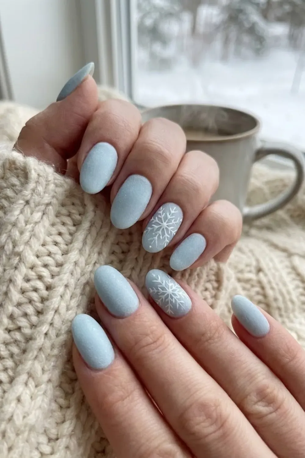 Matte Frosty Blue Oval Nails with Snowflakes – Matte light blue oval nails featuring delicate white snowflake nail art, a cozy and clean winter manicure style.