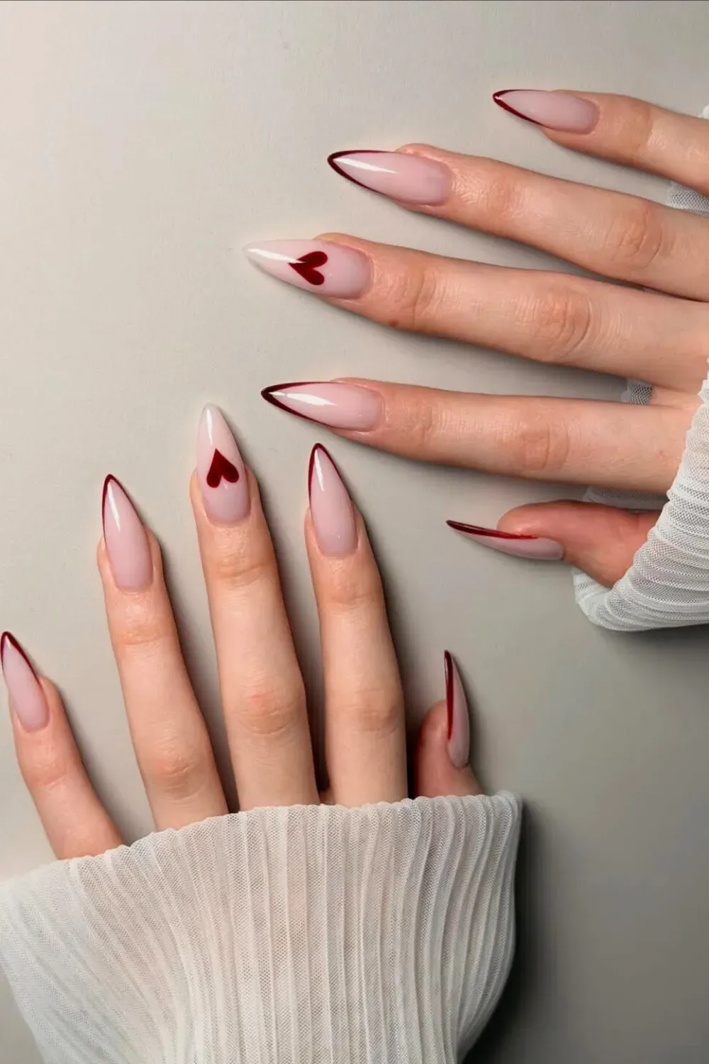 Deep Red French Tip and Heart Tip Stilettos – Sharp almond nails featuring deep red french tips and a heart-shaped tip accent.