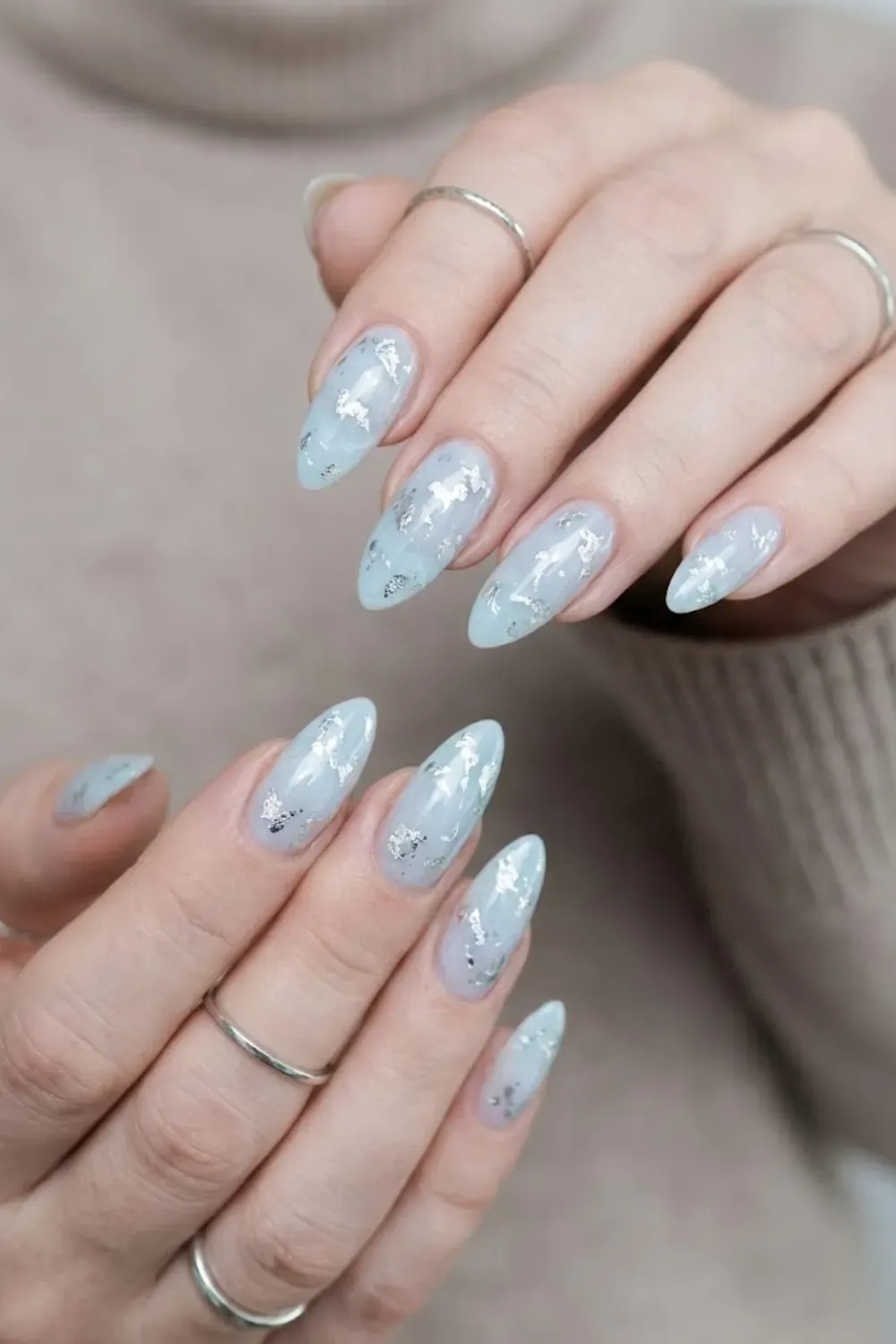 Icy Marble Stiletto Nails with Silver Foil – Pointed almond/stiletto nails featuring an icy blue marble design with metallic silver foil flakes for a textured winter look.