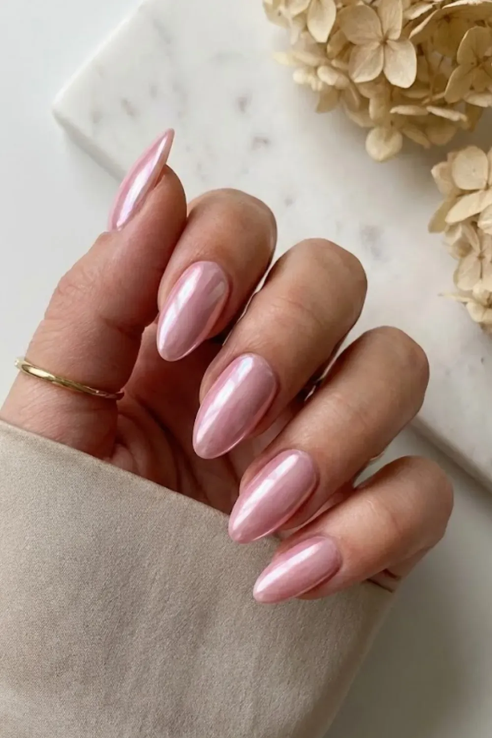 Long almond nails with a pink chrome glazed donut finish, catching the light.