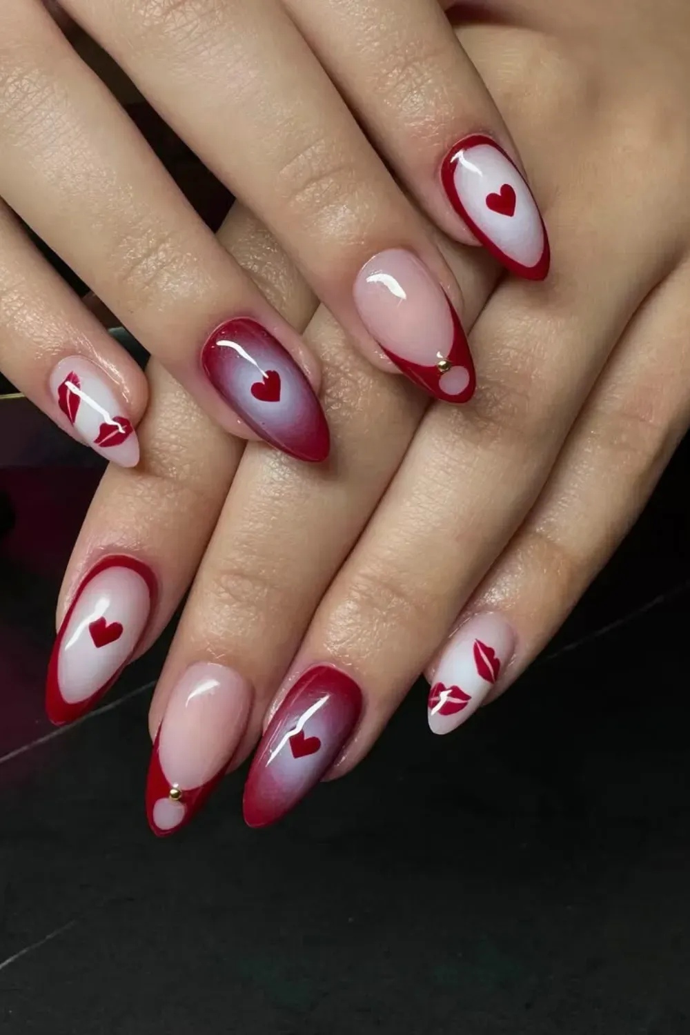 Red Aura Gradient Nails with Hearts and Lips – Almond nails with a red aura gradient, painted hearts, and kiss mark details.