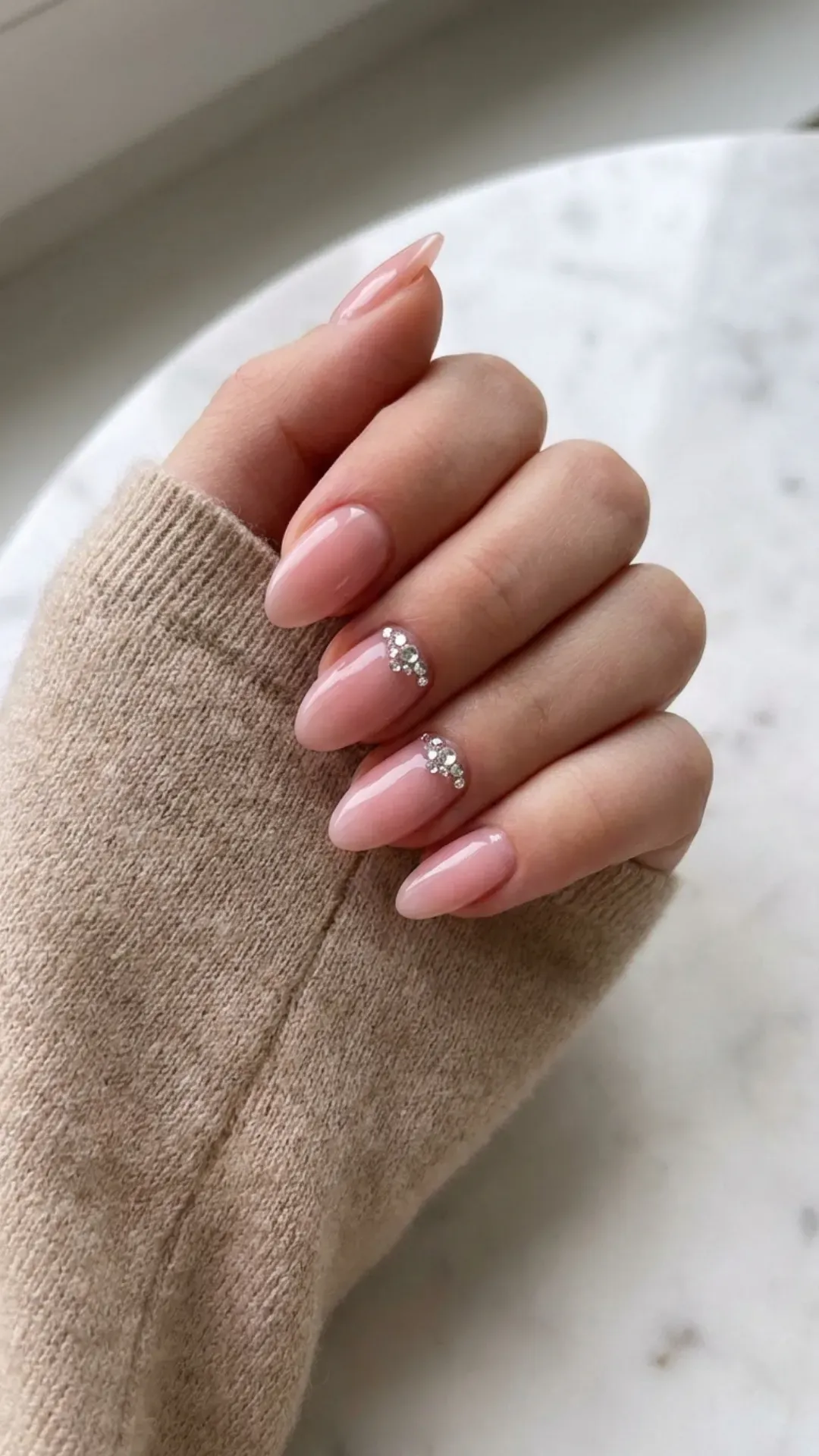 clear pink almond nails with small rhinestone accents