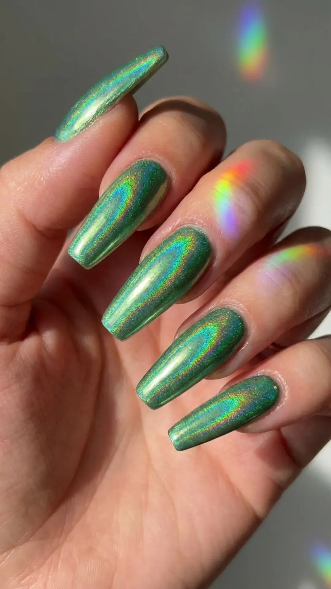 Holographic green nails reflecting rainbow light futuristic look