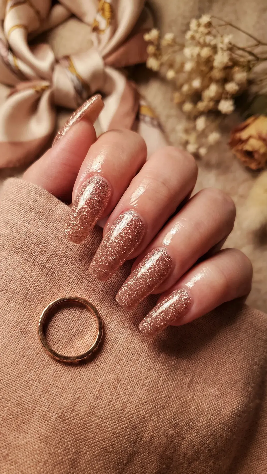 Long coffin nails with rose gold glitter sparkle, warm lighting with elegant styling