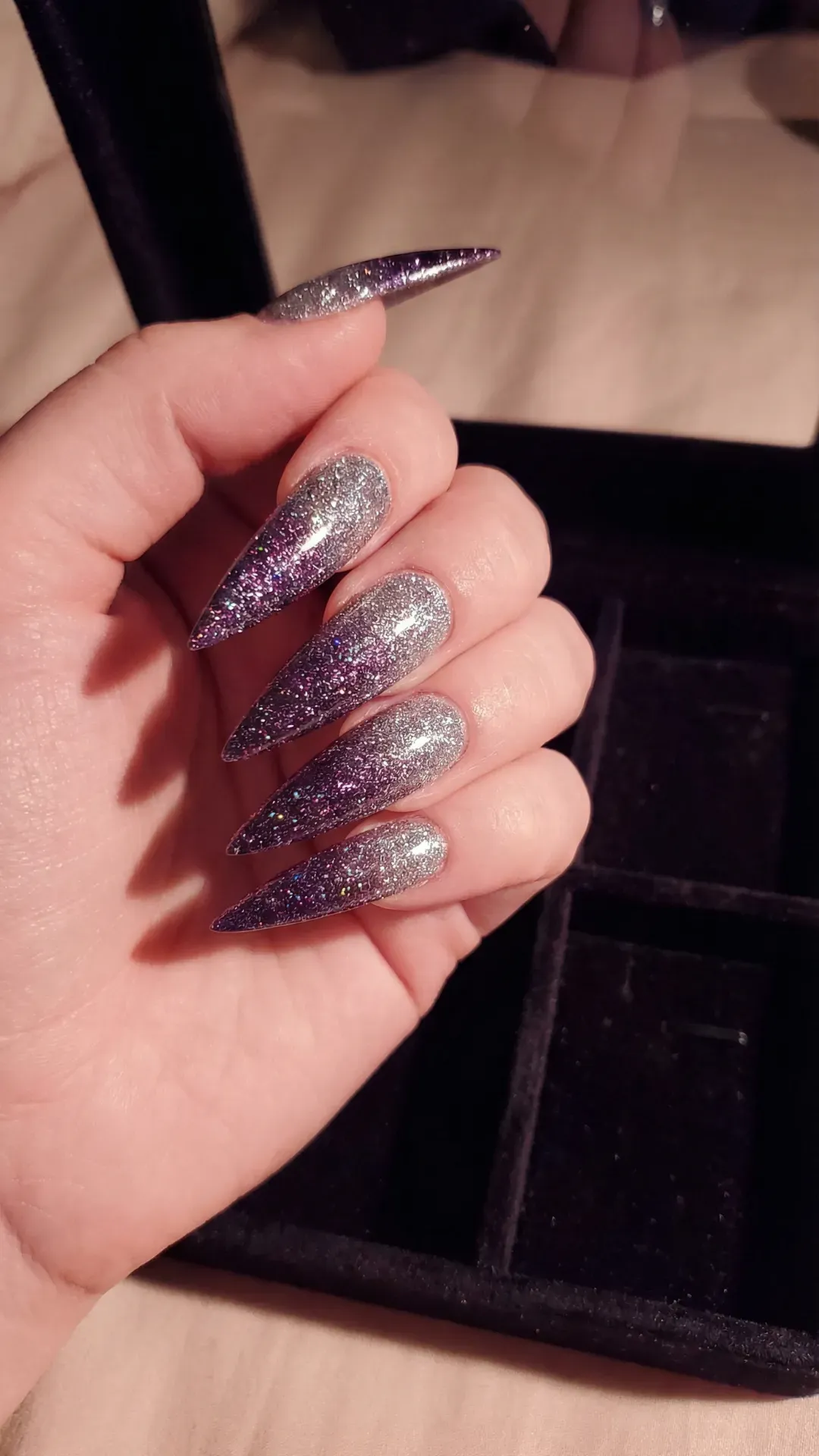 Extra-long stiletto nails with dark purple to silver glitter ombre, glossy finish, dark luxury background